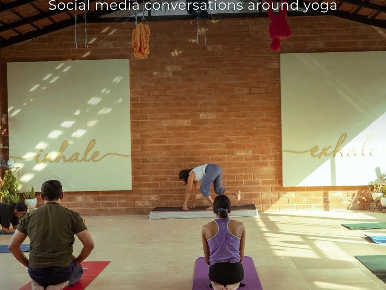 A yoga studio with participants practising on mats under warm natural light. Text overlay reads “The Social Media Buzz: Social media conversations around yoga,” followed by reflections on Yoga Day discussions about exercise, philosophy, tradition, culture